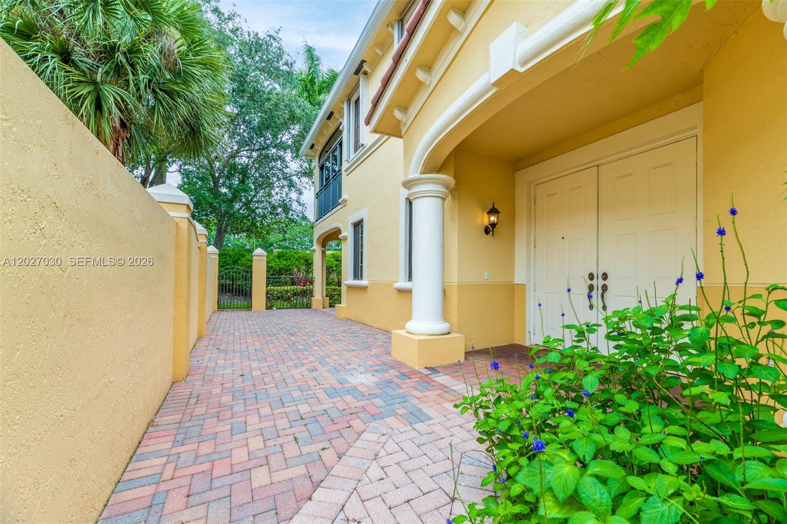 A paved walkway leads to a yellow house entrance with a white double door — 1695 Passion Vine Cir # 1, Weston FL 33326, WESTON, FL