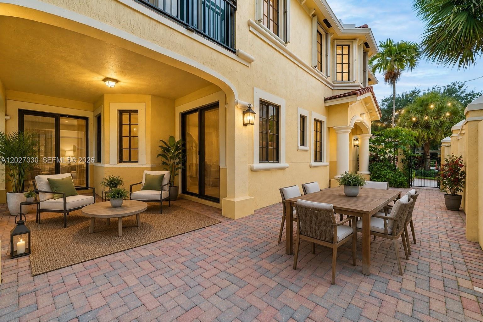 A paved patio features a dining set and a lounge area beside a yellow house — 1695 Passion Vine Cir # 1, Weston FL 33326, WESTON, FL