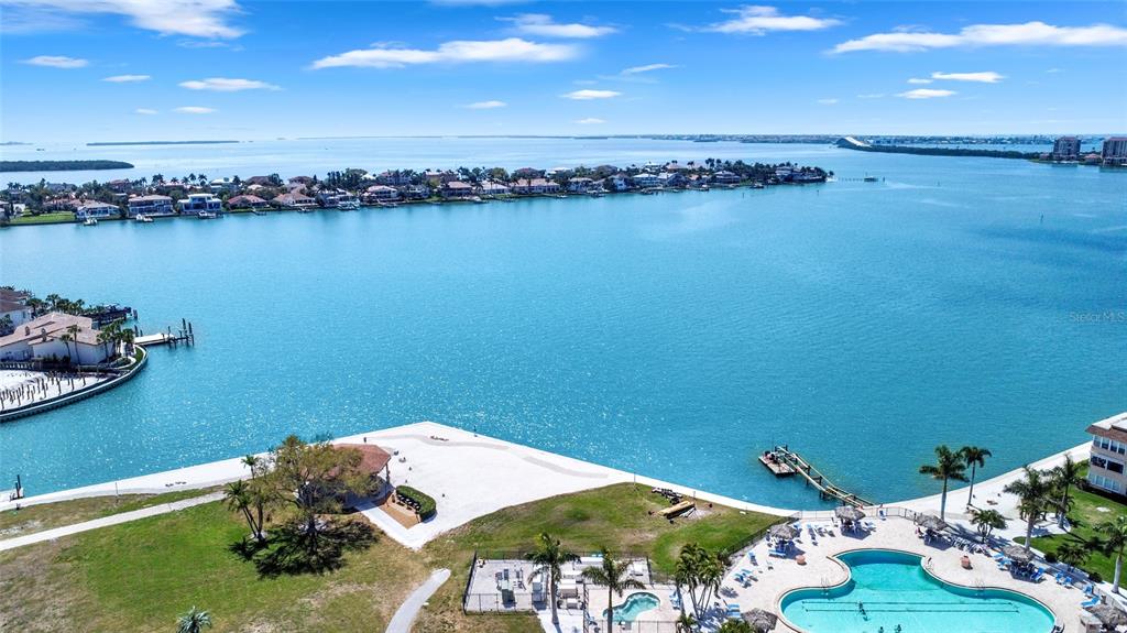 An aerial view shows a waterfront property with a pool, beach area, and boat dock — 4900 BRITTANY DRIVE S UNIT 301, ST PETERSBURG, FL