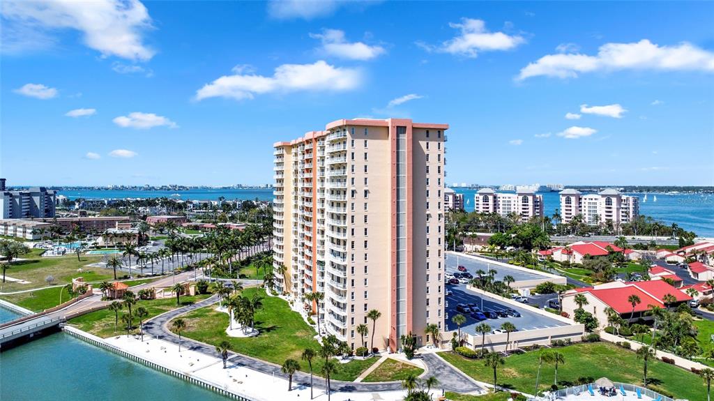 An aerial view shows a tall, tan residential building surrounded by parking lots and water — 4900 BRITTANY DRIVE S UNIT 301, ST PETERSBURG, FL