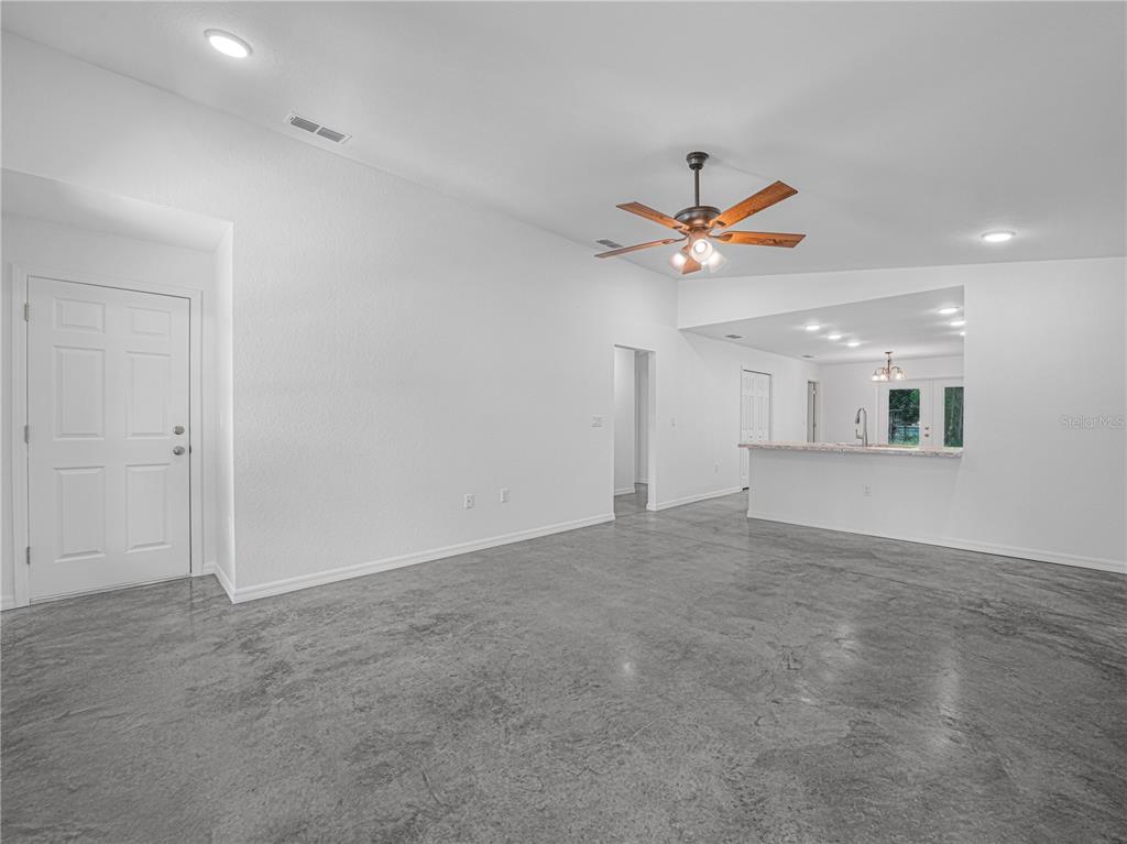 A spacious living room features white walls, a ceiling fan, and polished concrete flooring — 118 HIGHLAND AVENUE, AUBURNDALE, FL