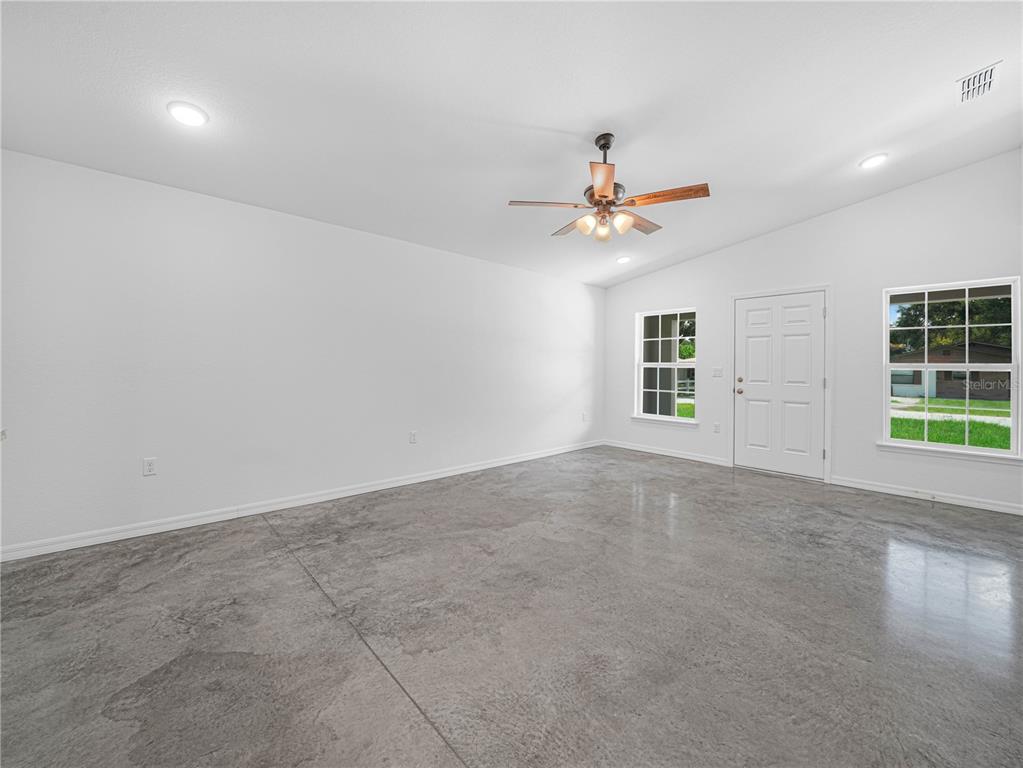 An empty room with white walls, a ceiling fan, and polished gray concrete flooring — 118 HIGHLAND AVENUE, AUBURNDALE, FL