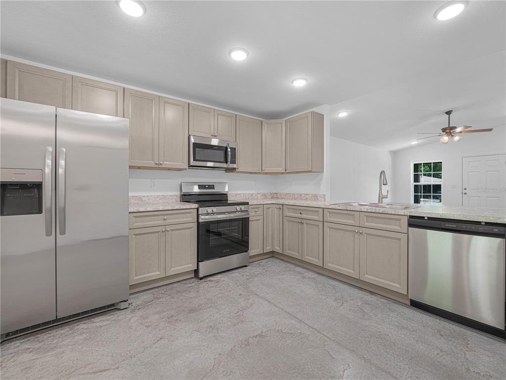 A kitchen with light-colored cabinets, stainless steel appliances, and a concrete floor — 118 HIGHLAND AVENUE, AUBURNDALE, FL