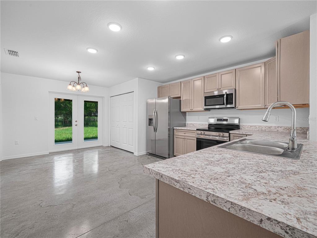 A kitchen with light wood cabinets, stainless steel appliances, and a concrete floor — 118 HIGHLAND AVENUE, AUBURNDALE, FL