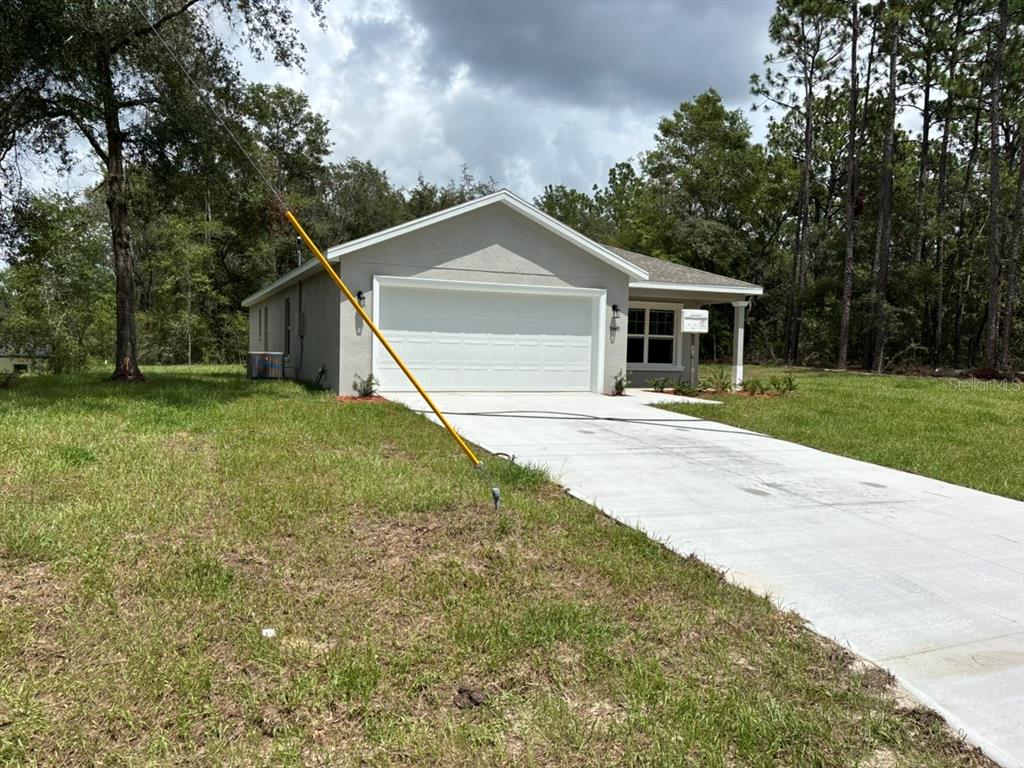 A single-story house with a concrete driveway and a garage sits on a grassy lot — 9449 N CORTLANDT DRIVE, DUNNELLON, FL