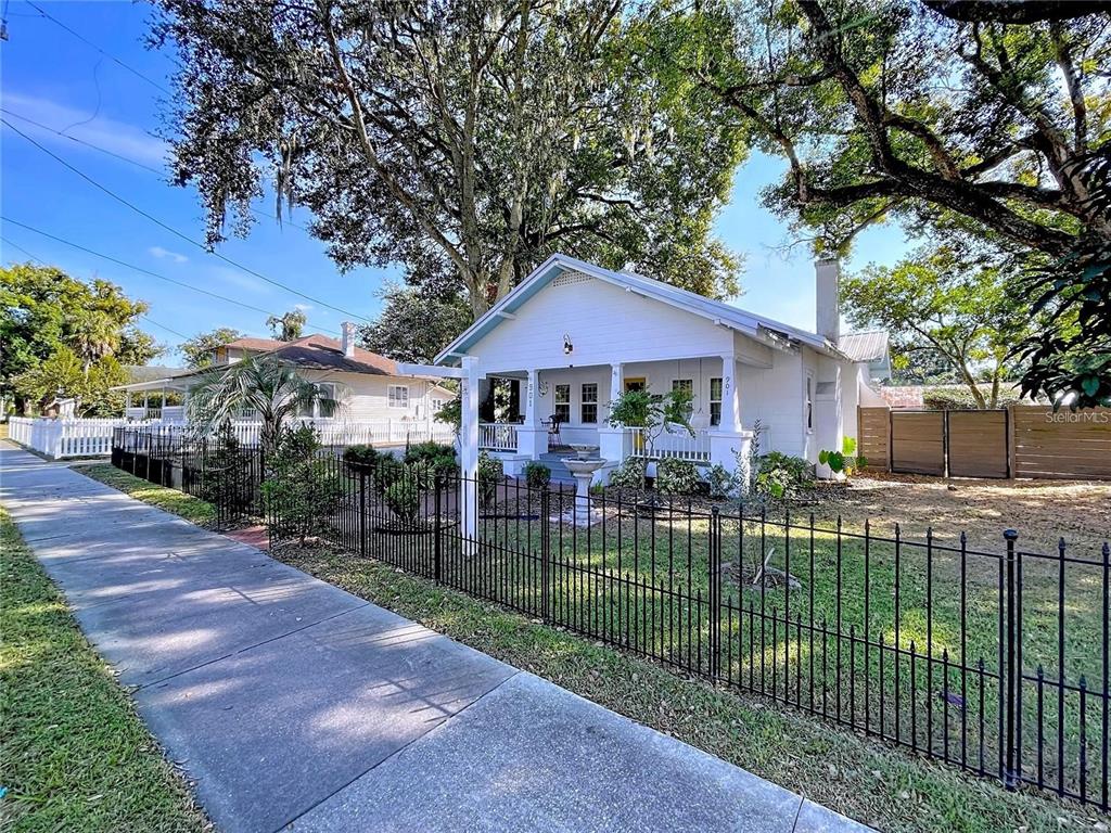 A white bungalow with a front porch sits behind a black metal fence — 901 W BAKER STREET, PLANT CITY, FL