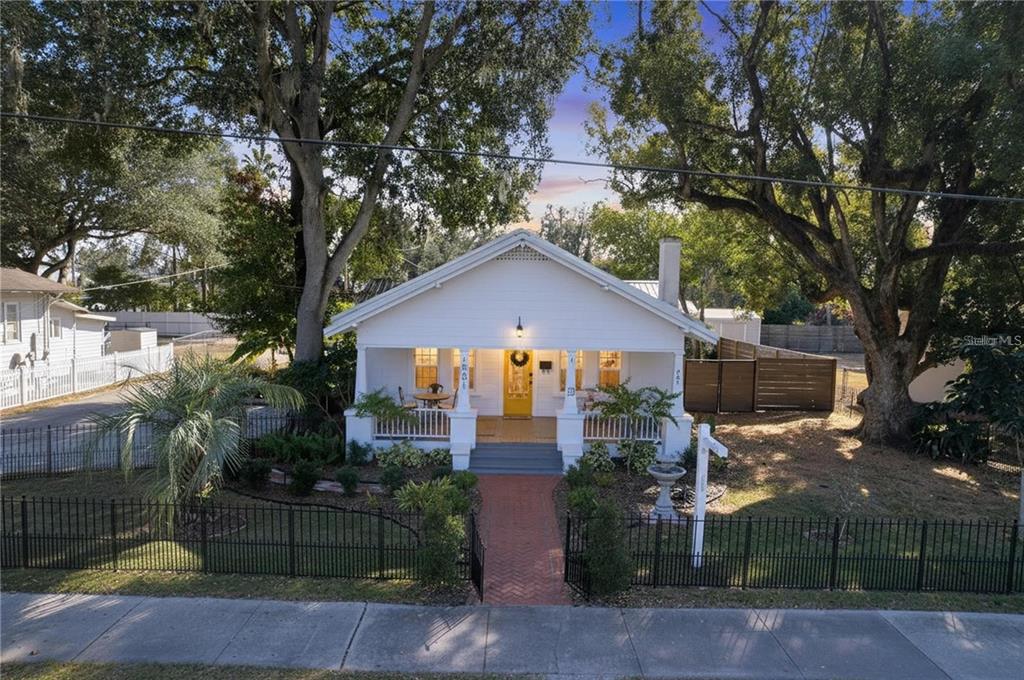 A white bungalow with a front porch and brick walkway sits behind a black fence — 901 W BAKER STREET, PLANT CITY, FL