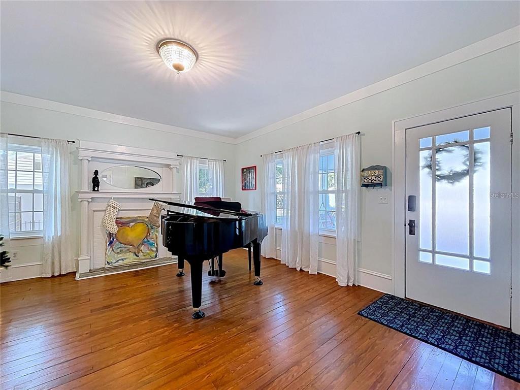 A living room features a grand piano, a fireplace, hardwood floors, and a front door — 901 W BAKER STREET, PLANT CITY, FL