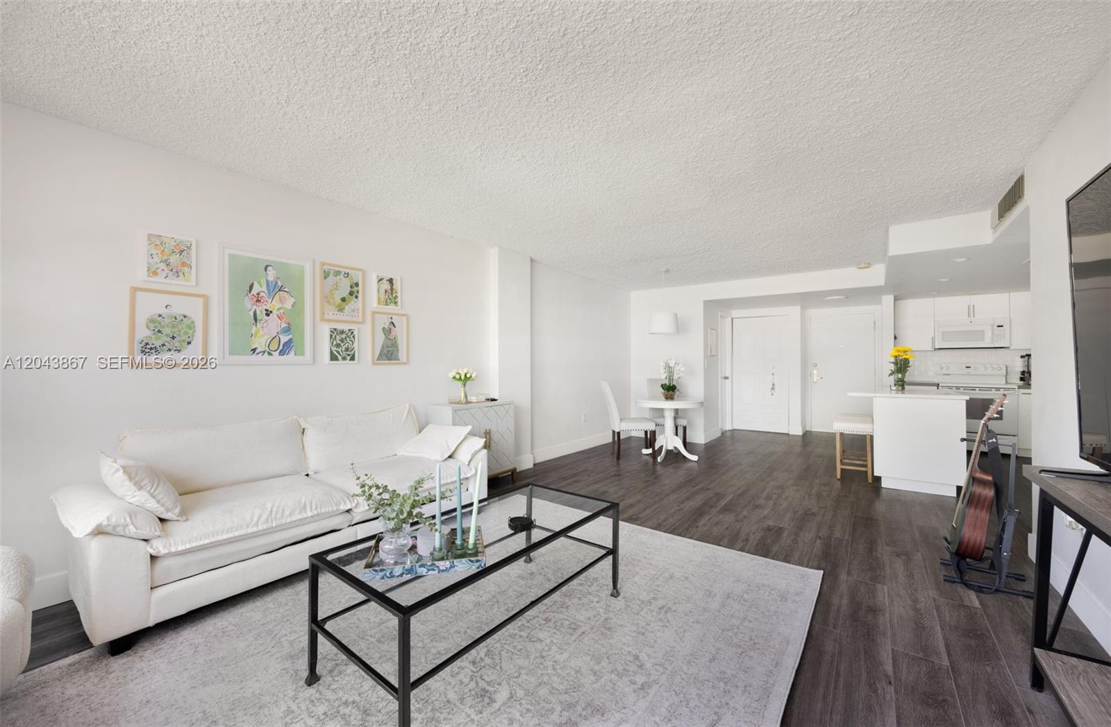 A living room features a white sofa, glass coffee table, and an open kitchen area — 150 SE 25th Rd # 2J, Miami FL 33129, MIAMI, FL