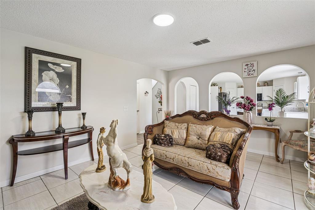 A living room features arched wall openings, tiled floors, and traditional furniture — 7 BOLTON COURT, KISSIMMEE, FL
