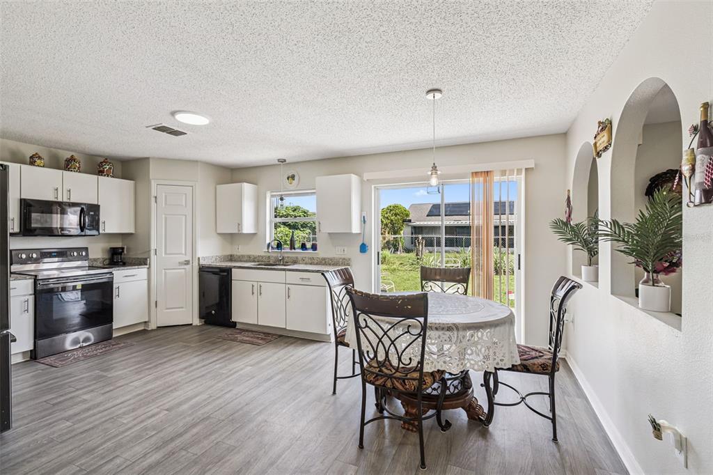 A kitchen and dining area with white cabinets, stainless appliances, and a sliding glass door — 7 BOLTON COURT, KISSIMMEE, FL