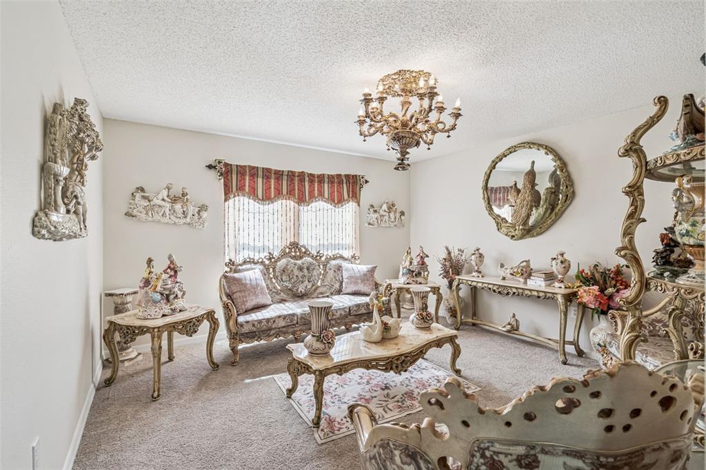 A formal living room features ornate gold-toned furniture, a crystal chandelier, and decorative wall sculptures — 7 BOLTON COURT, KISSIMMEE, FL