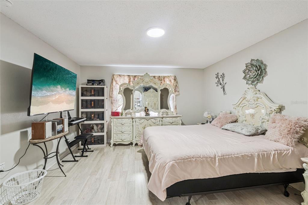 A bedroom features a large bed, a white ornate dresser with a mirror, and a television — 7 BOLTON COURT, KISSIMMEE, FL