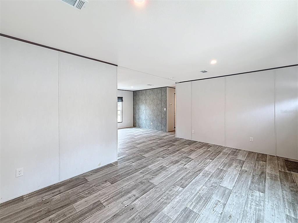 An interior view of a room with white walls, wood-look flooring, and a doorway — 150 LAKE GALILEE DRIVE, HAWTHORNE, FL