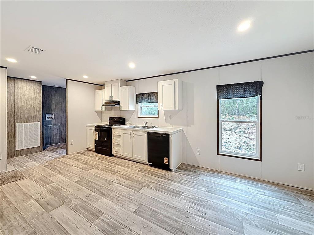 A kitchen with white cabinets, black appliances, and light wood-look flooring — 150 LAKE GALILEE DRIVE, HAWTHORNE, FL