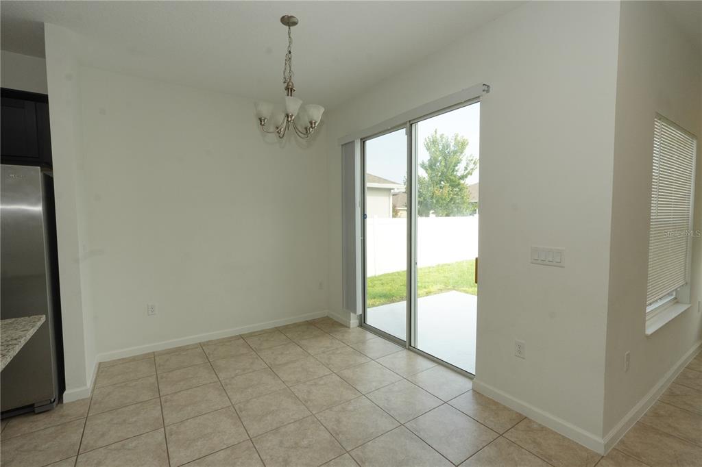 A dining area features tile flooring, a chandelier, and a sliding glass door to a patio — 3552 PATRON AVENUE, DELTONA, FL