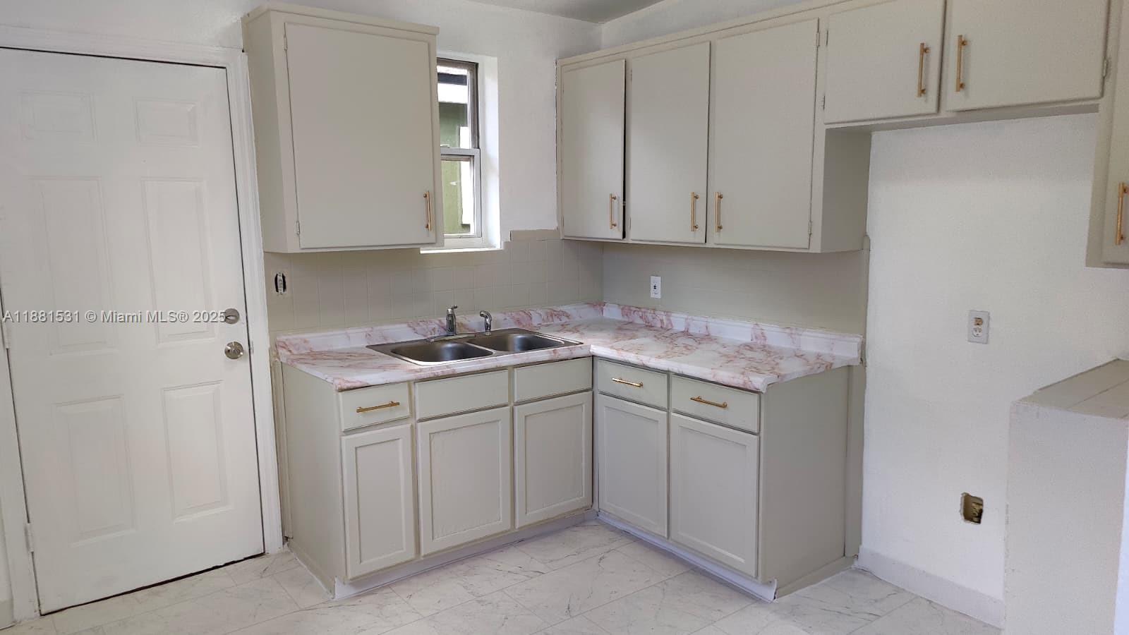 A kitchen features light-colored cabinets, a marble-patterned countertop, and a double-basin stainless steel sink — 1630 Barnett ST, Jacksonville FL 32209, JACKSONVILLE, FL