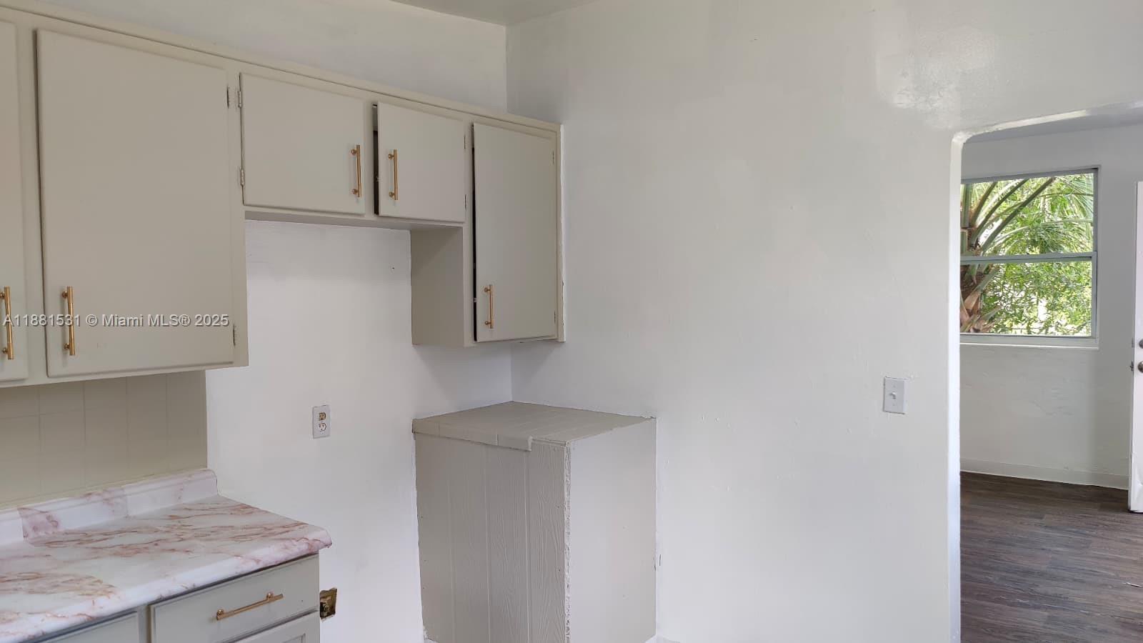 A kitchen features light-colored cabinets, a marble-patterned countertop, and an adjacent doorway to another room — 1630 Barnett ST, Jacksonville FL 32209, JACKSONVILLE, FL