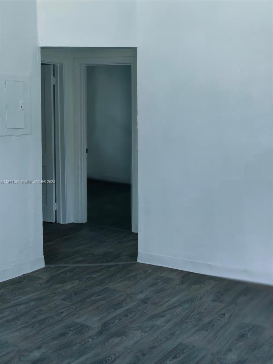 A room with white walls and dark wood-look flooring leads to an open doorway — 1630 Barnett ST, Jacksonville FL 32209, JACKSONVILLE, FL