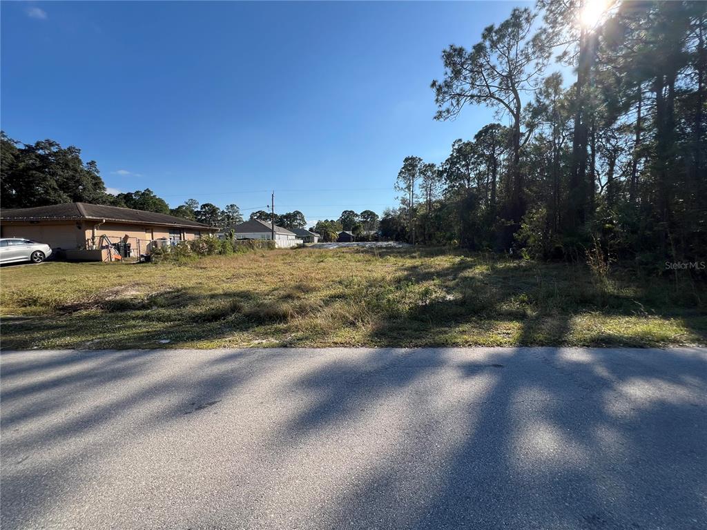 A vacant, grassy residential lot sits between a house and a wooded area — 442 LACKLAND STREET SW, PALM BAY, FL