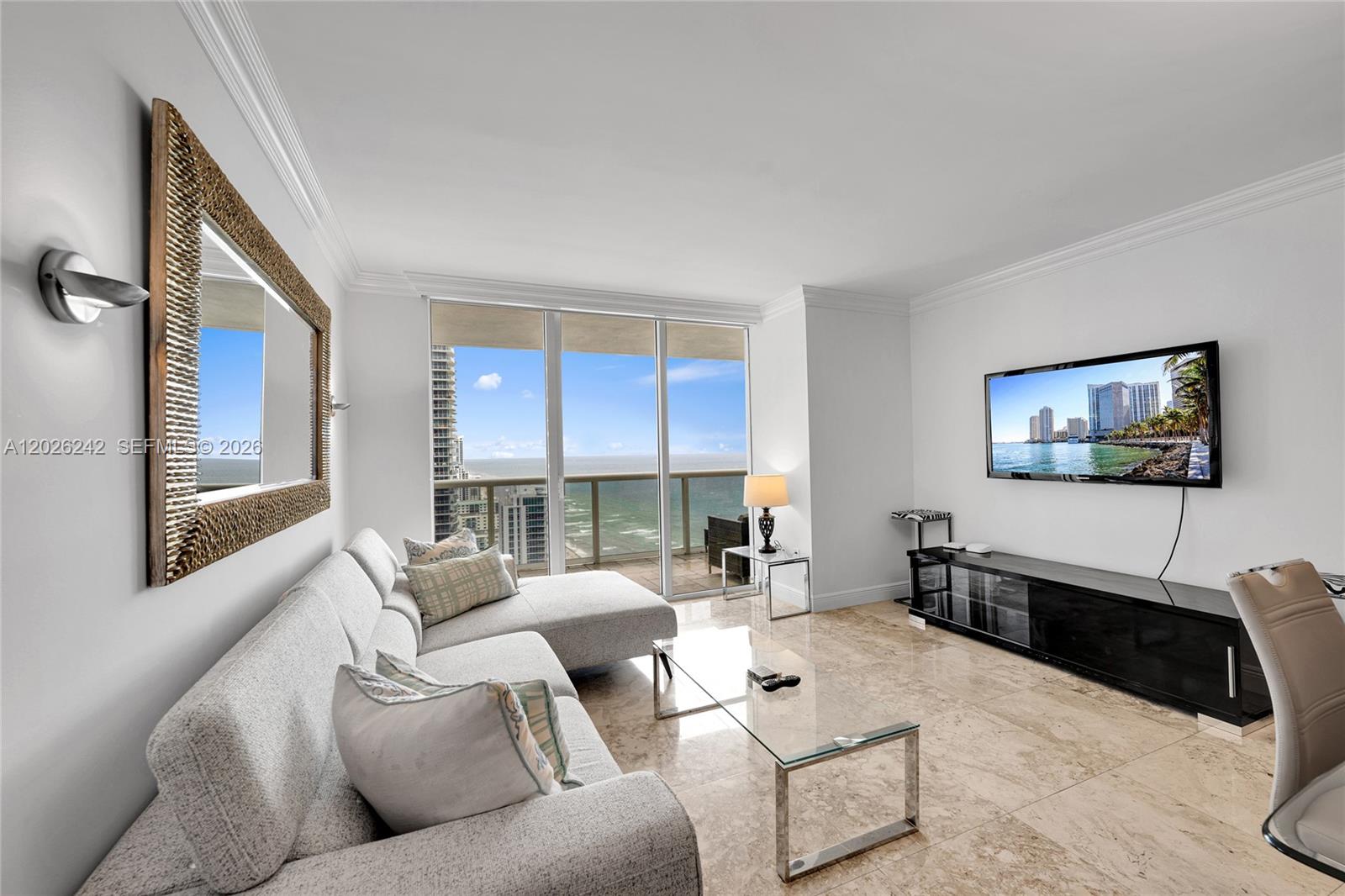 A living room features a light gray sectional sofa, glass coffee table, and ocean views — 1830 S OCEAN DR # 3310, Hallandale Beach FL 33009, HALLANDALE BEACH, FL