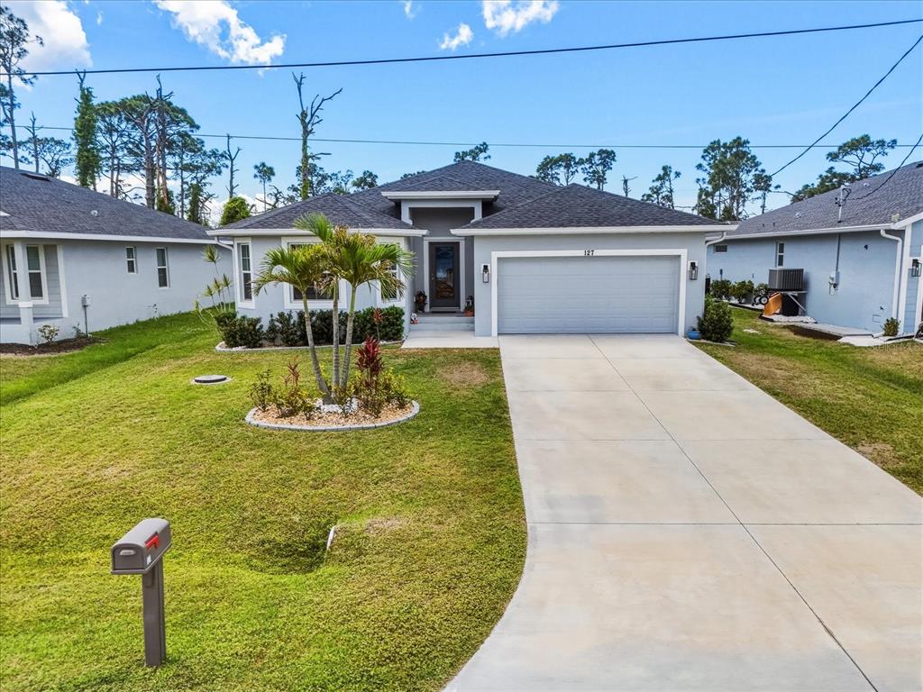 A single-story gray house with a two-car garage and a palm tree in the yard — 127 GLADES DRIVE, ROTONDA WEST, FL