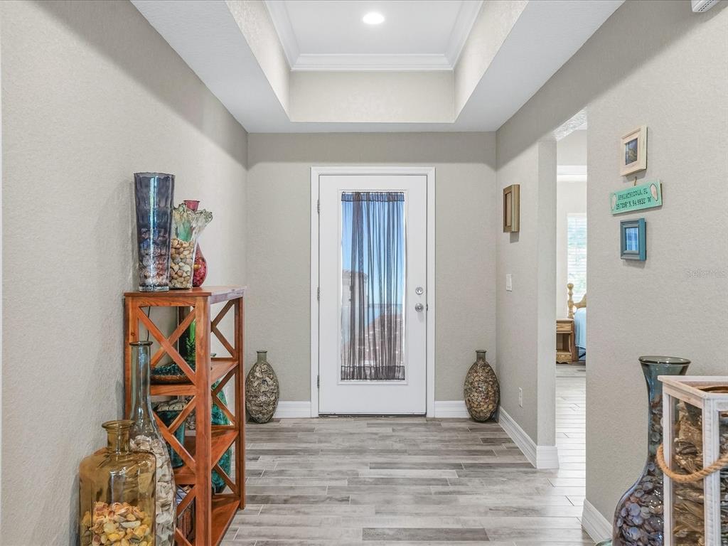 A bright entryway features a white front door, wood-look tile flooring, and a tray ceiling — 127 GLADES DRIVE, ROTONDA WEST, FL