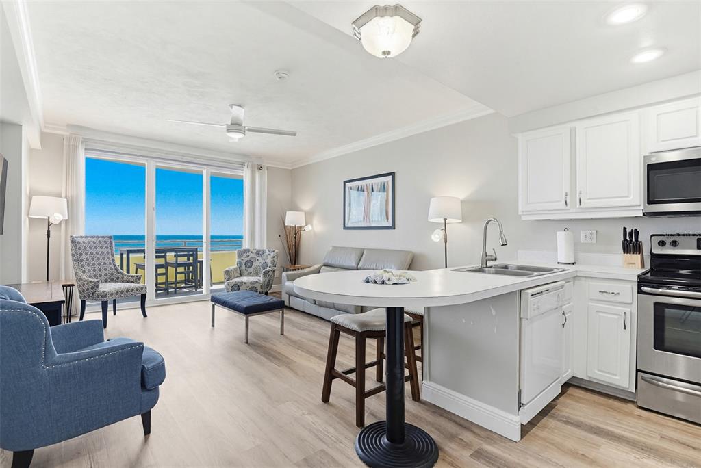 A bright living room and kitchen area features light wood flooring and a balcony view — 300 N ATLANTIC AVENUE UNIT 1505, DAYTONA BEACH, FL