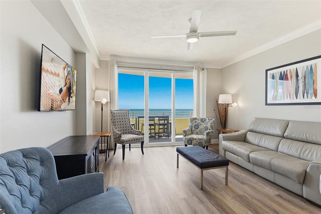 A living room features light wood floors, a leather sofa, and a balcony overlooking ocean — 300 N ATLANTIC AVENUE UNIT 1505, DAYTONA BEACH, FL
