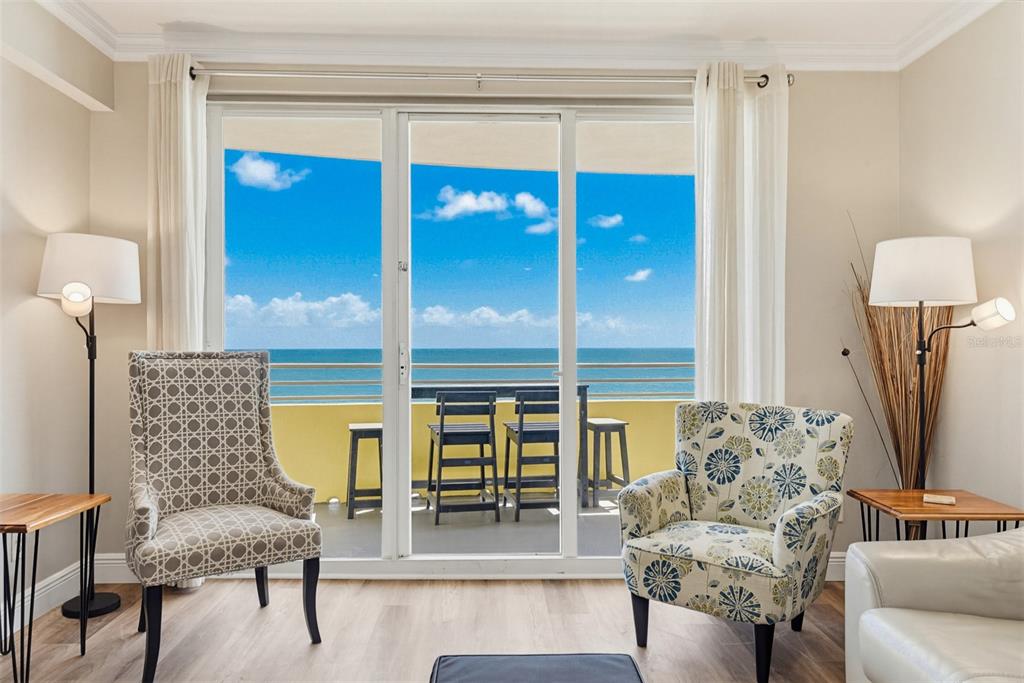 A living room with two patterned armchairs, floor lamps, and a balcony overlooking the ocean — 300 N ATLANTIC AVENUE UNIT 1505, DAYTONA BEACH, FL