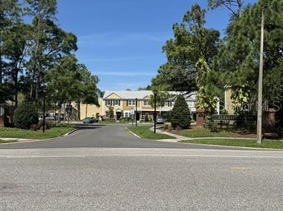 A view of a residential street leading toward a multi-story apartment complex with trees — 12326 BERKELEY SQUARE DRIVE, TAMPA, FL