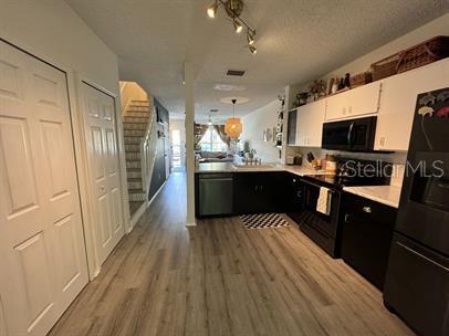 A kitchen with dark cabinets and light wood-look flooring opens to a living area — 12326 BERKELEY SQUARE DRIVE, TAMPA, FL