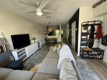A living room features a sectional sofa, a television on a media console, and flooring — 12326 BERKELEY SQUARE DRIVE, TAMPA, FL