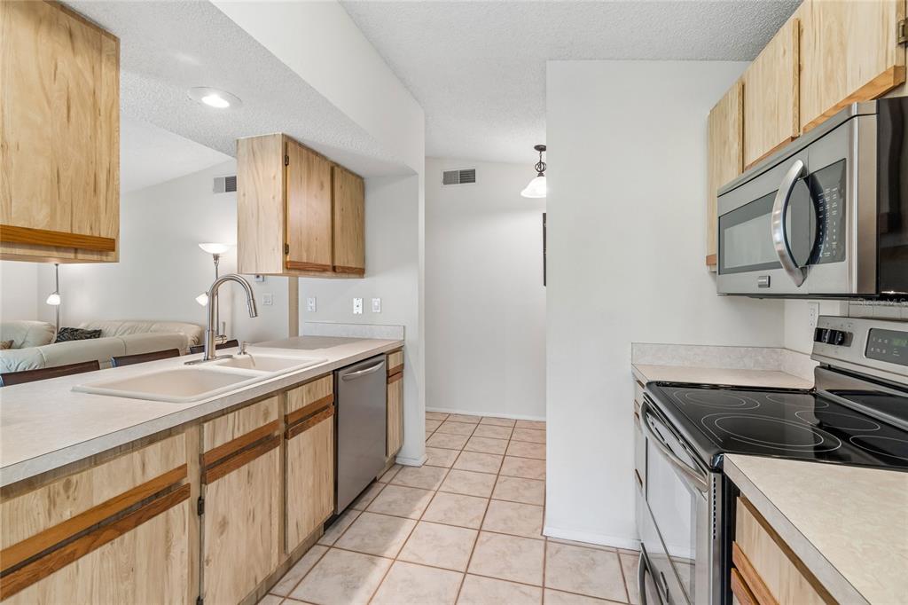 A kitchen features light wood cabinets, stainless steel appliances, and tile flooring — 10305 TURKEY OAK DRIVE, NEW PORT RICHEY, FL