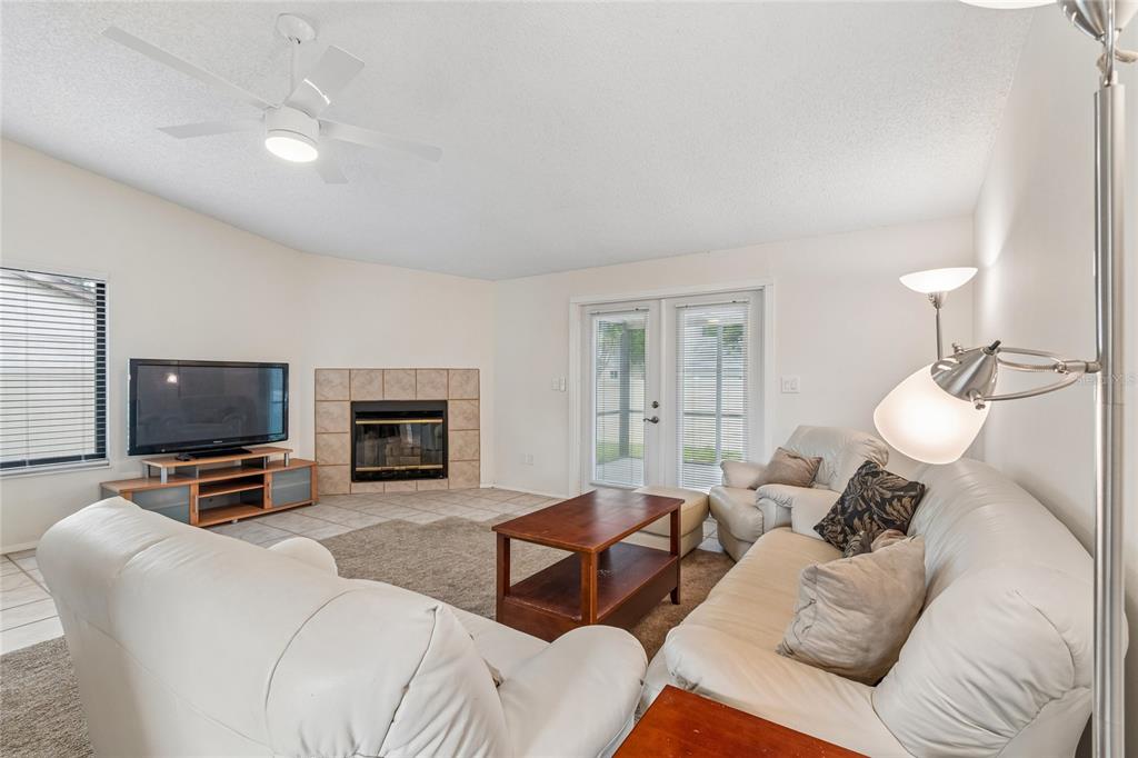 A living room features a fireplace, white leather sofas, a coffee table, and glass doors — 10305 TURKEY OAK DRIVE, NEW PORT RICHEY, FL