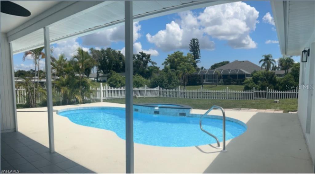 A covered patio overlooks a swimming pool with an attached spa and a fenced backyard — 257 BUNKER ROAD, ROTONDA WEST, FL