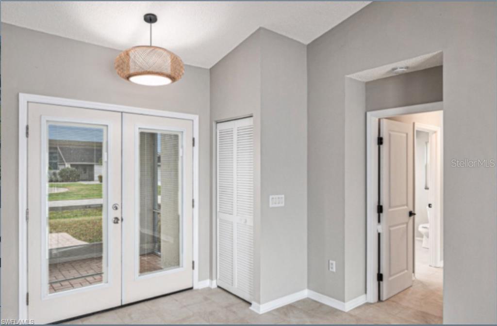 A room with light tile flooring, a textured pendant light, and a white louvered closet door — 257 BUNKER ROAD, ROTONDA WEST, FL