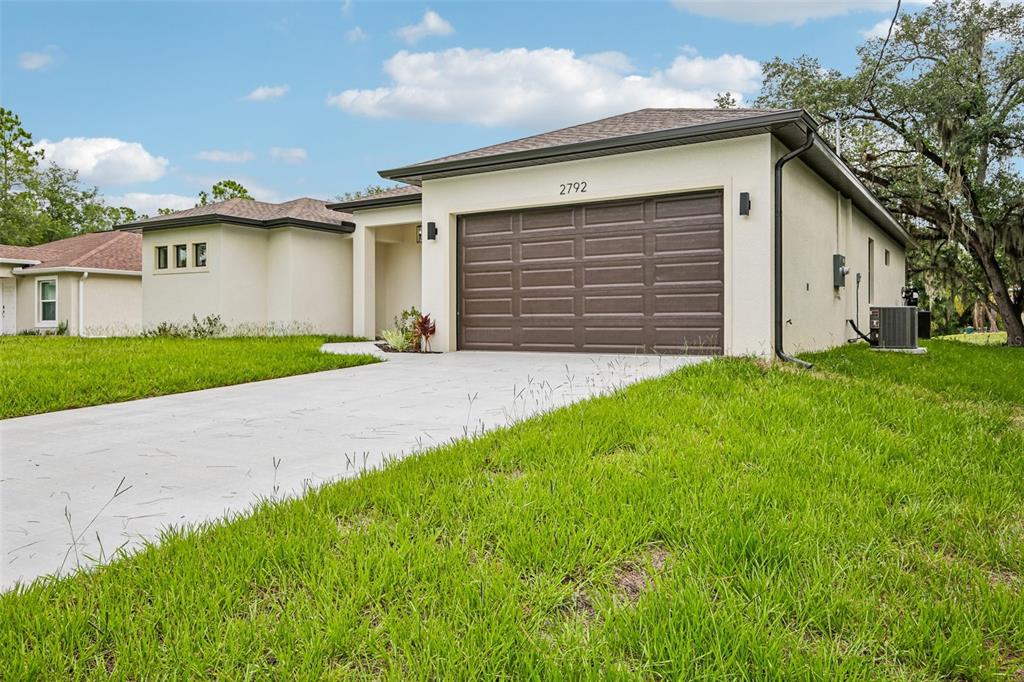 A single-story house with a brown garage door, light-colored stucco walls, and a concrete driveway — 2792 ABBEVILLE ROAD, NORTH PORT, FL