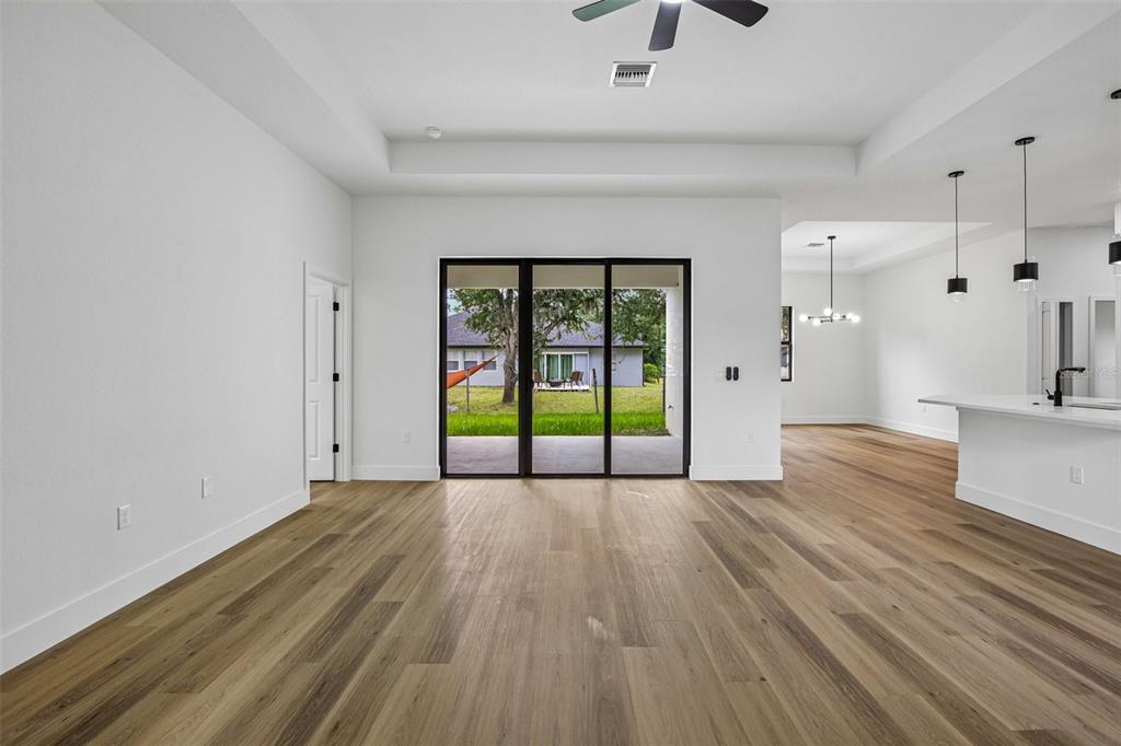 A bright living room features light wood flooring, a tray ceiling, and sliding glass doors — 2792 ABBEVILLE ROAD, NORTH PORT, FL