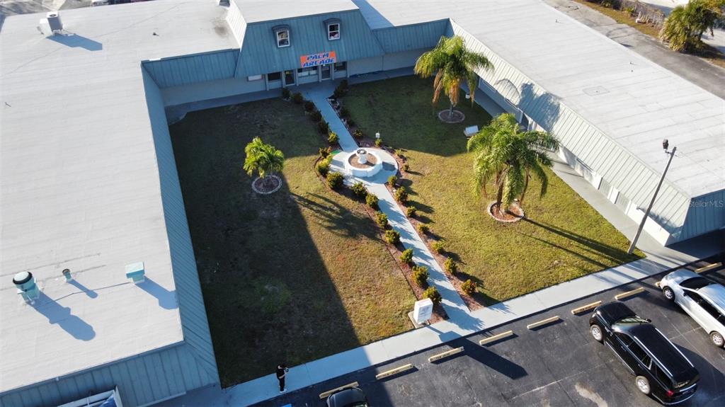 An aerial view shows a U-shaped commercial building with a central courtyard and fountain — 37548 US HWY 19 N, PALM HARBOR, FL