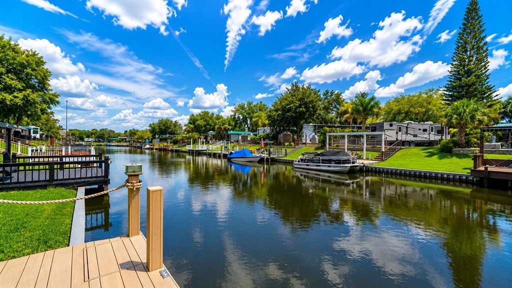 A wooden dock overlooks a canal with boats and recreational vehicles parked along the grassy banks — 453 WATERWAY DRIVE, LAKE WALES, FL
