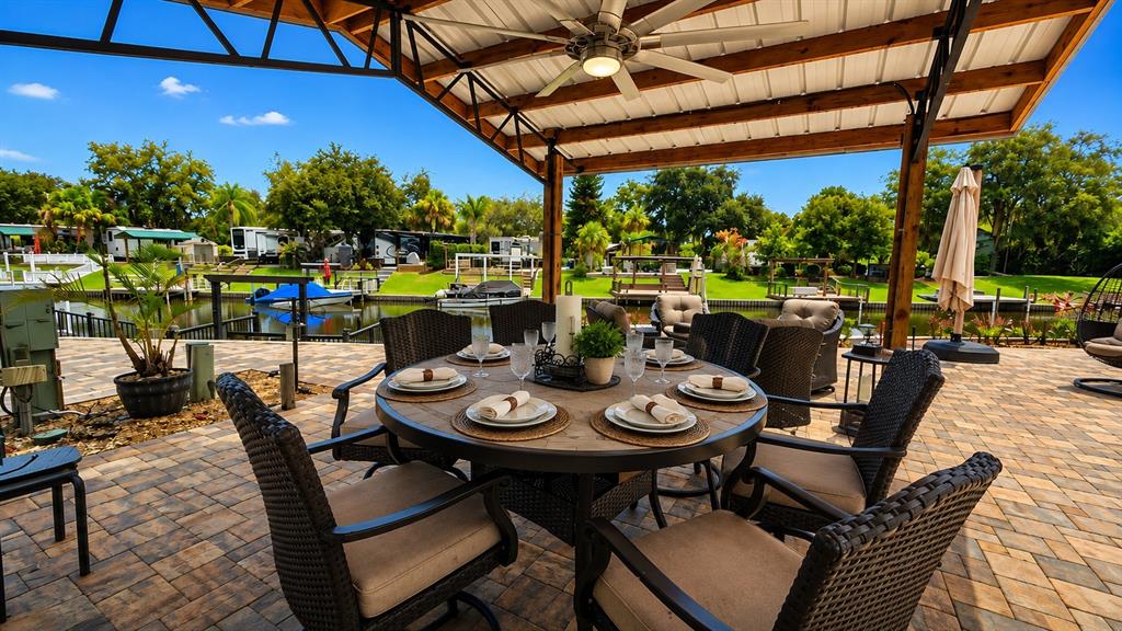 A patio with a dining set under a covered structure overlooking a canal and boats — 453 WATERWAY DRIVE, LAKE WALES, FL