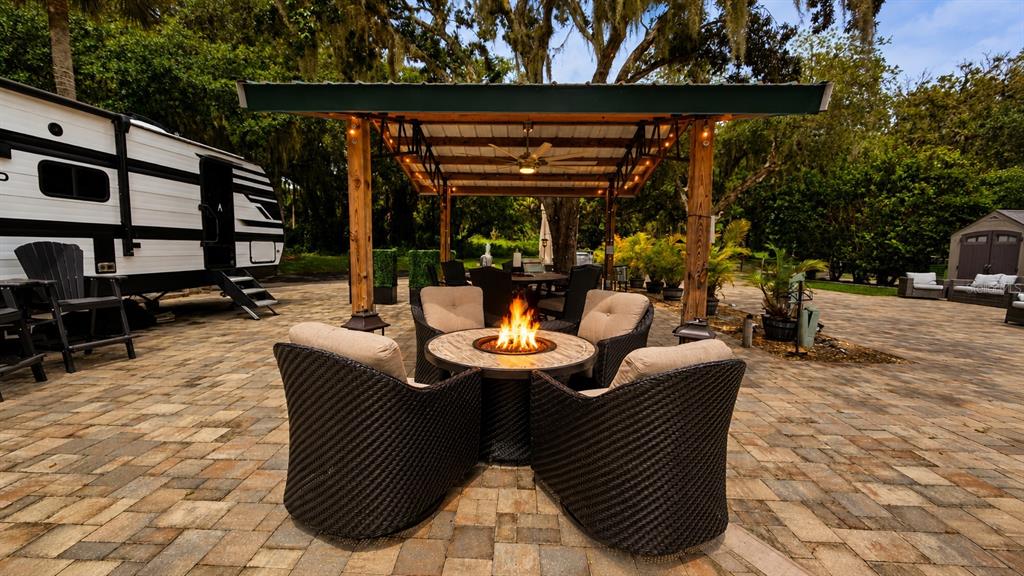 An outdoor patio features a fire pit with wicker chairs under a wooden pergola — 453 WATERWAY DRIVE, LAKE WALES, FL