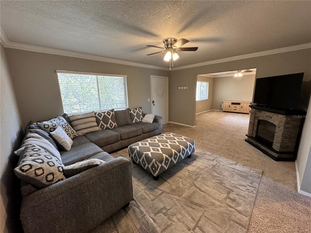 A living room features a gray sectional sofa, a patterned ottoman, and a stone fireplace — 120 BLUE POINT WAY UNIT 320, ALTAMONTE SPRINGS, FL
