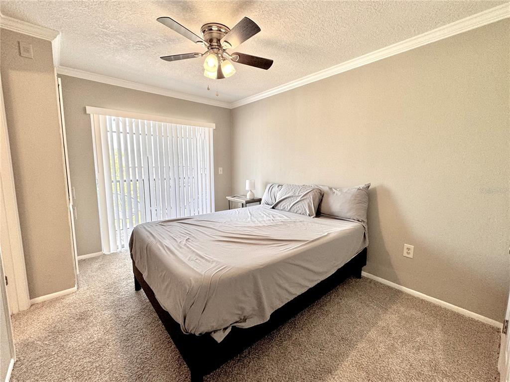 A bedroom features a bed with grey bedding, a ceiling fan, and sliding glass doors — 120 BLUE POINT WAY UNIT 320, ALTAMONTE SPRINGS, FL