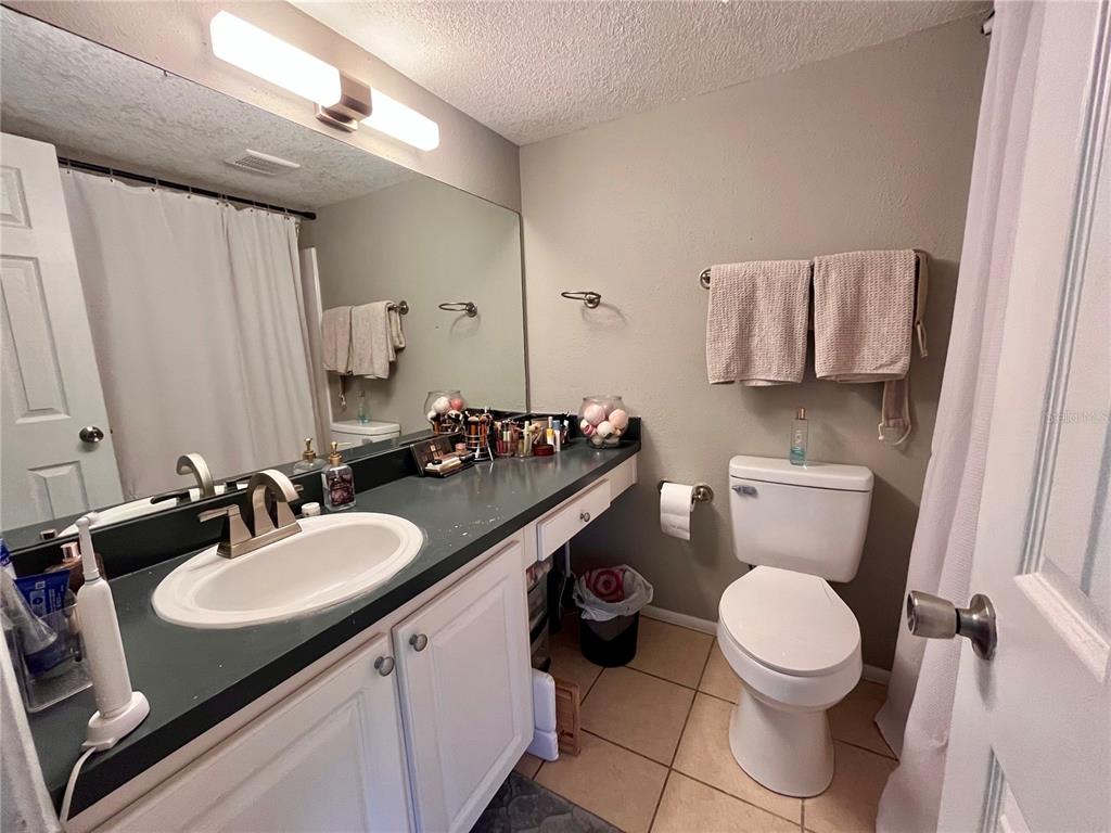A bathroom features a white vanity with a dark countertop, a toilet, and a mirror — 120 BLUE POINT WAY UNIT 320, ALTAMONTE SPRINGS, FL