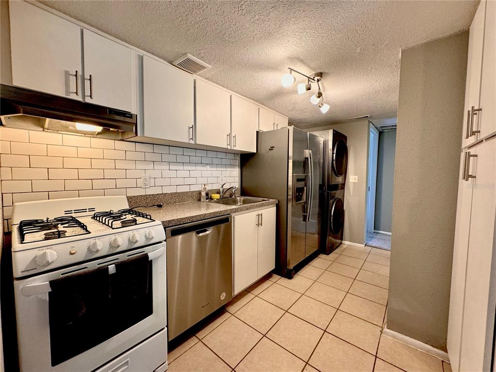 A kitchen features white cabinets, stainless steel appliances, a tiled backsplash, and a tiled floor — 120 BLUE POINT WAY UNIT 320, ALTAMONTE SPRINGS, FL
