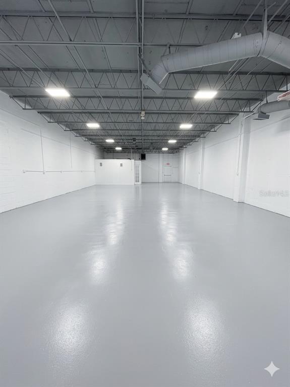 An empty commercial warehouse space with white walls, a gray epoxy floor, and exposed ceiling — 4055 7TH TERRACE, ST PETERSBURG, FL