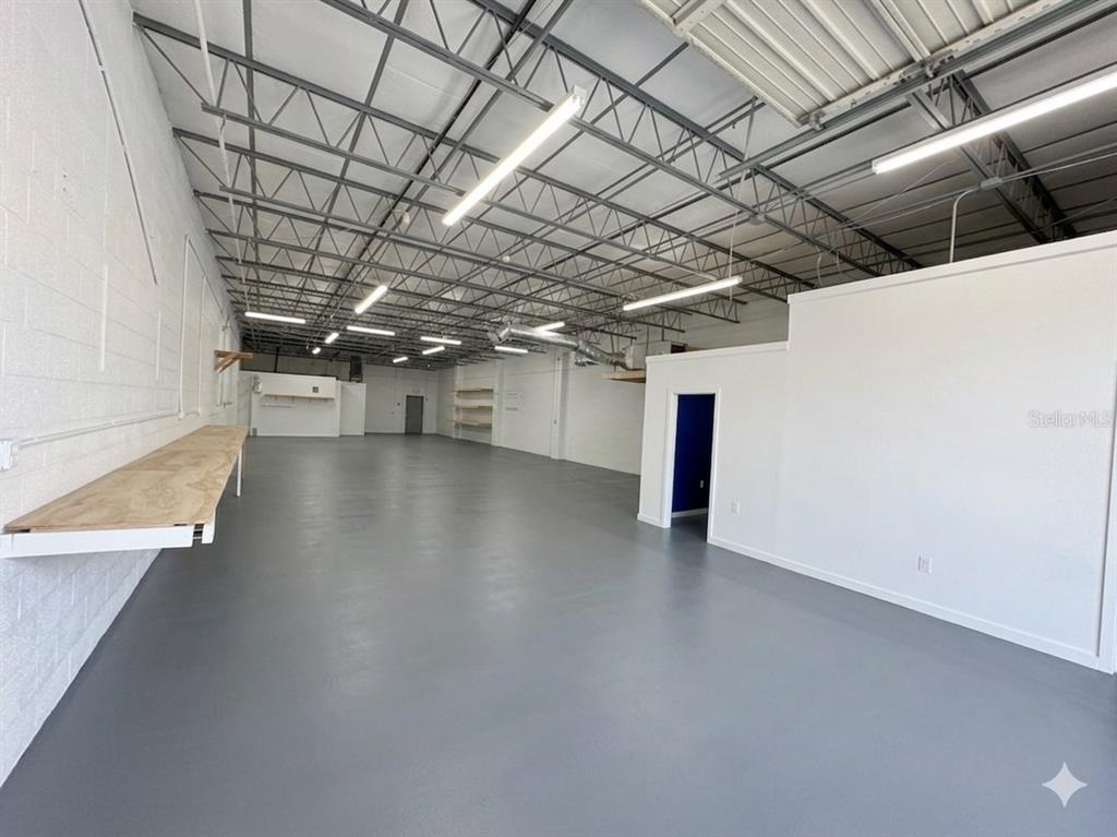 An empty industrial warehouse space features a gray concrete floor, white walls, and exposed ceiling trusses — 4055 7TH TERRACE, ST PETERSBURG, FL