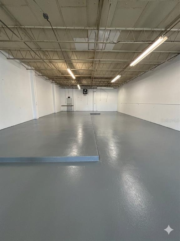 An empty industrial warehouse space features a gray epoxy floor and exposed ceiling rafters — 4055 7TH TERRACE, ST PETERSBURG, FL